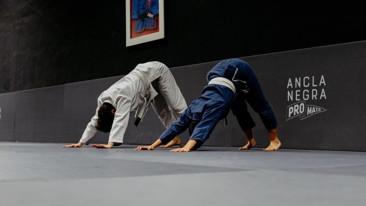 Two martial artists practice stretching exercises in a dojo in Buenos Aires.
